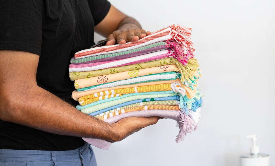 Close-up of a person holding neatly stacked, vibrant towels against a white background.