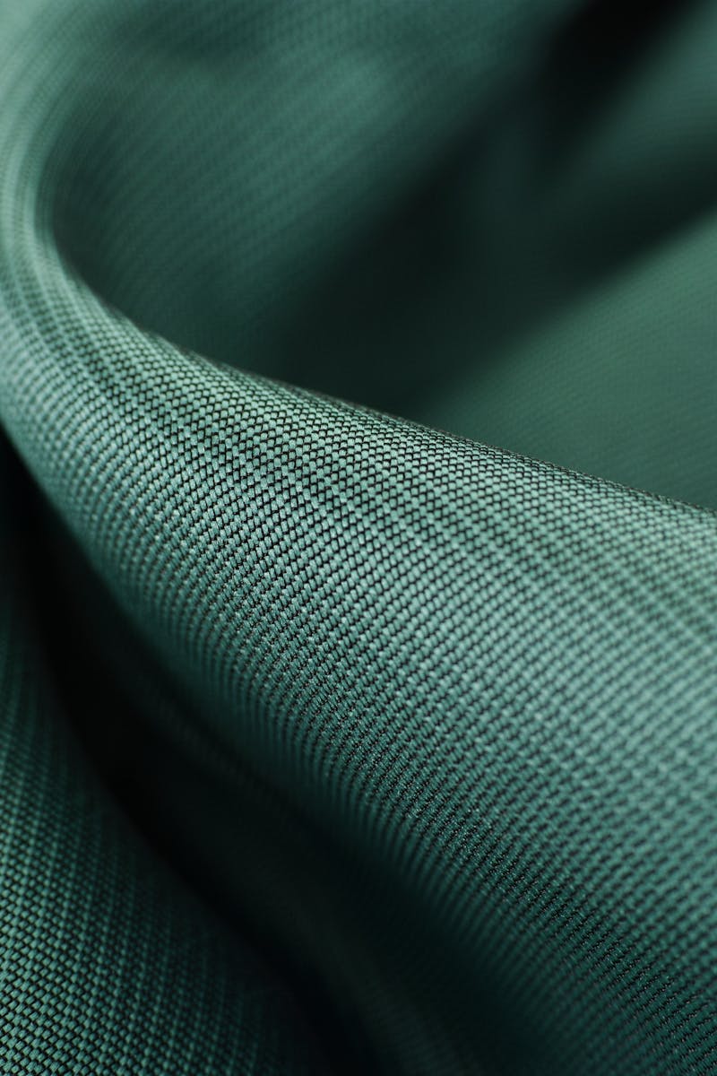 Home Close-up texture shot of elegant green satin fabric highlighting its smooth and soft surface.