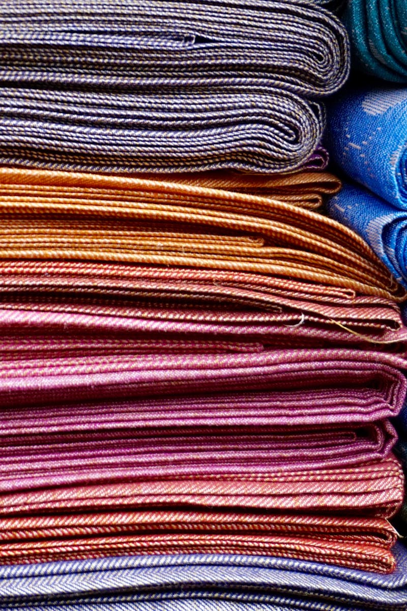 Home Vibrant and neatly stacked fabrics showcasing an array of colors and patterns, ideal for fashion and textile design.