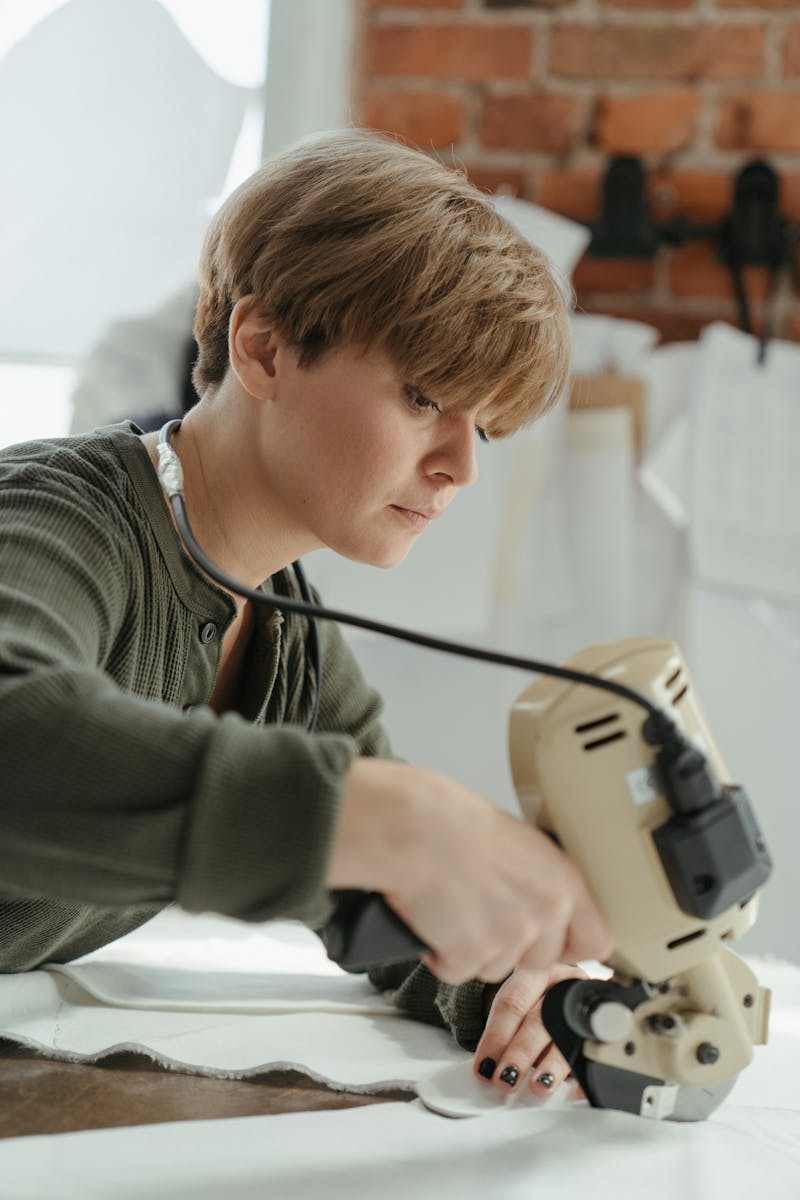 Home A seamstress carefully cuts fabric with a rotary cutter in a sunlit workshop.